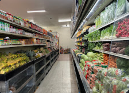 Produce aisle with bananas and fruit on one side and refrigerated vegetables on the other